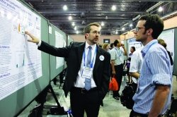 Photo of Jesse Thompson (left) of the University of Kentucky explaining his research during the Academic Employment Initiative at Sci-Mix at the ACS national meeting in Philadelphia.